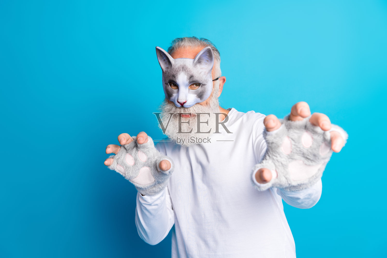 穿着猫咪主题角色扮演服的老年男子，背景为蓝色，展示了创意风格和猫咪色彩的配饰。照片摄影图片