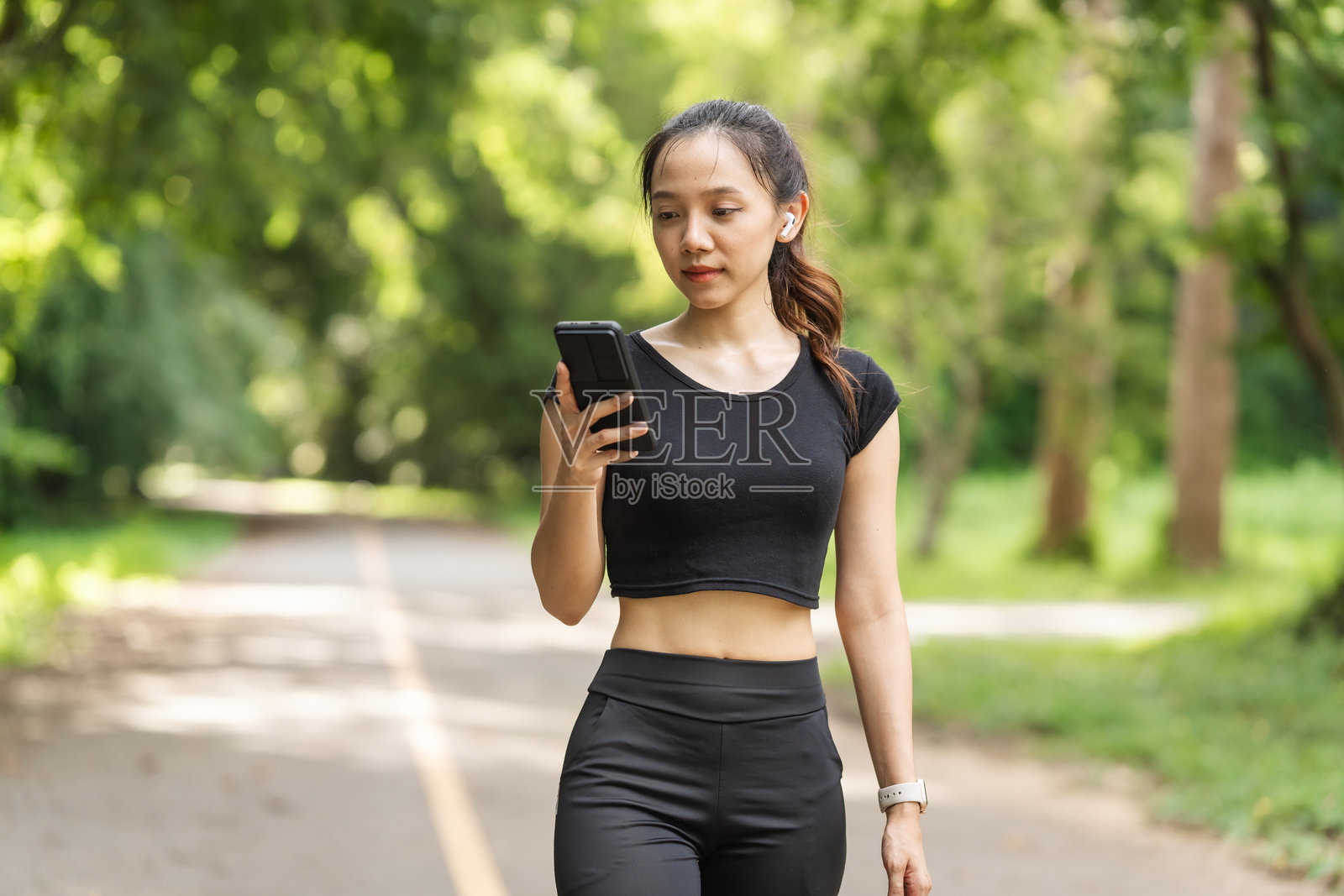 一位穿着运动服的女性在公园里跑步，享受新鲜空气，参与户外活动以保持健康的生活方式，增强心血管健康，感到快乐和充满活力。照片摄影图片