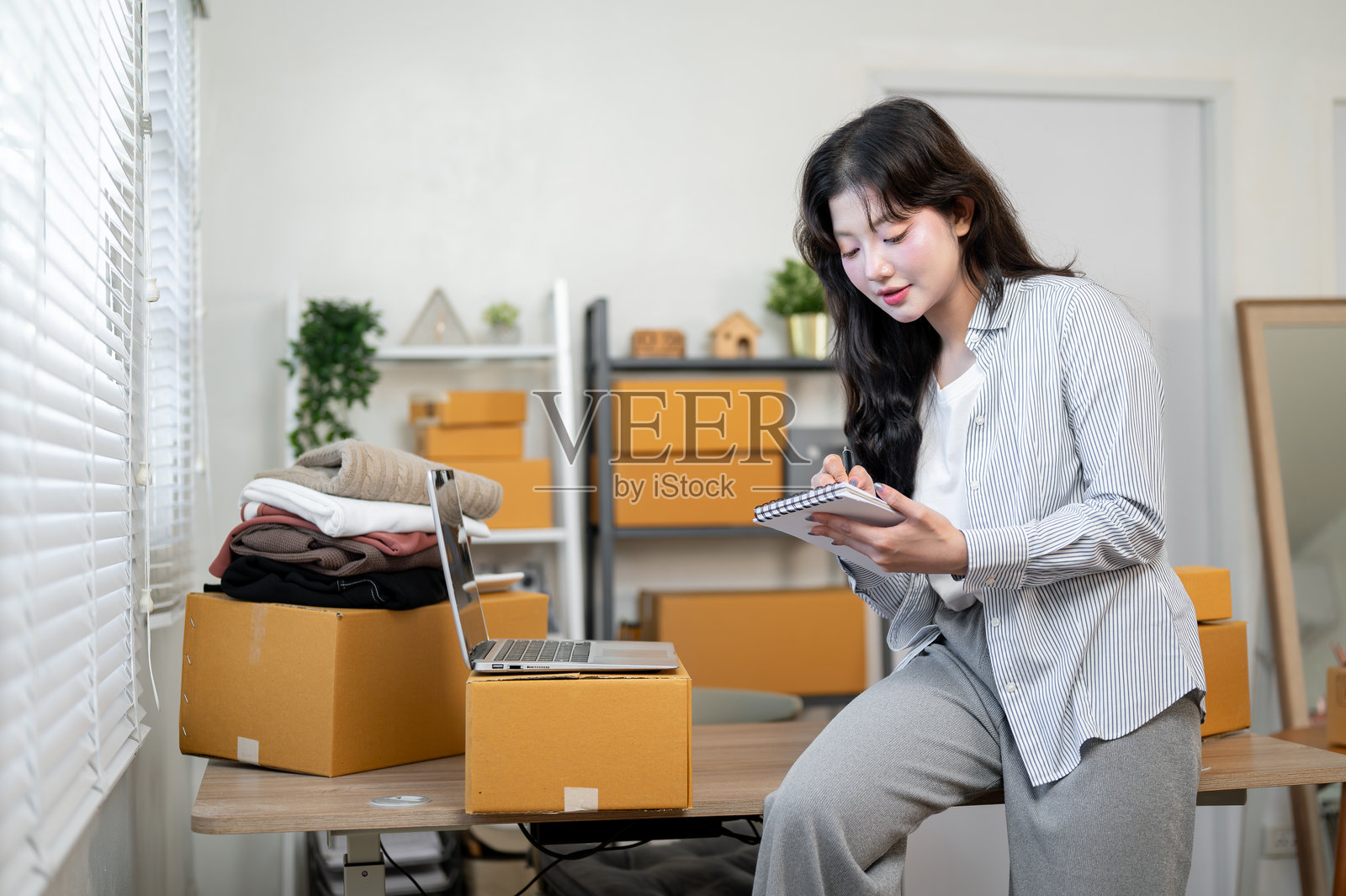 一位专注的亚洲女性企业家在家中的办公室里坐在桌前，正在列清单。照片摄影图片