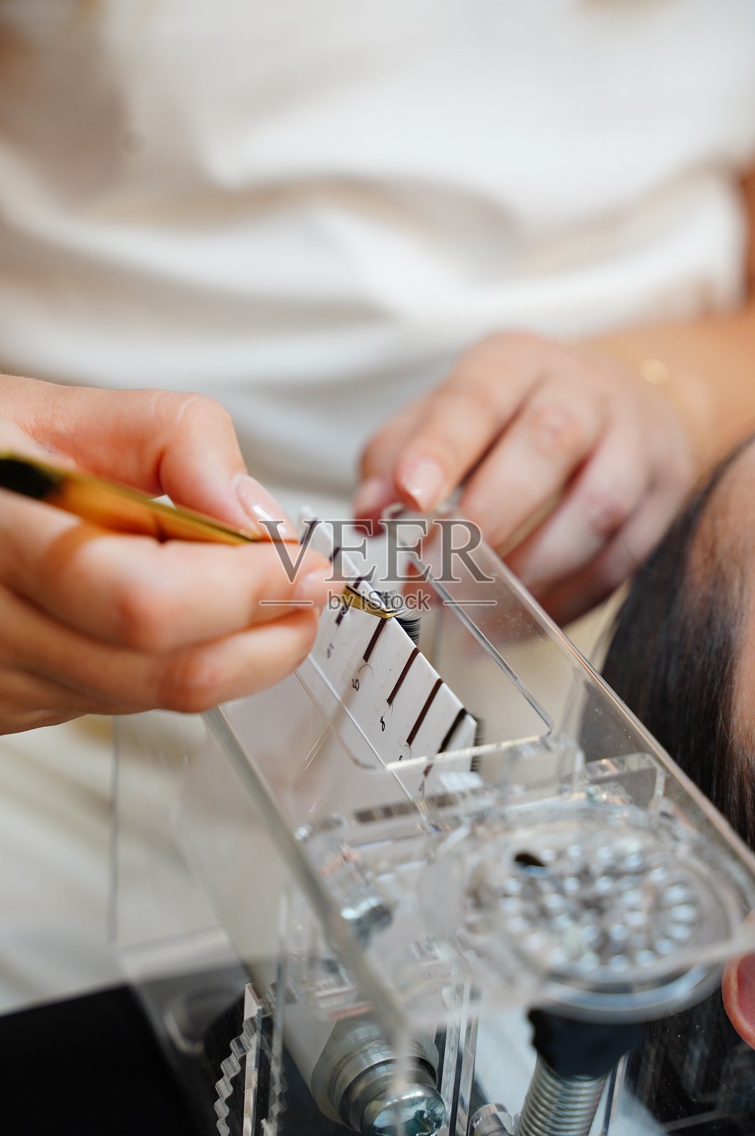 美容师正在准备假睫毛以进行粘贴。照片摄影图片