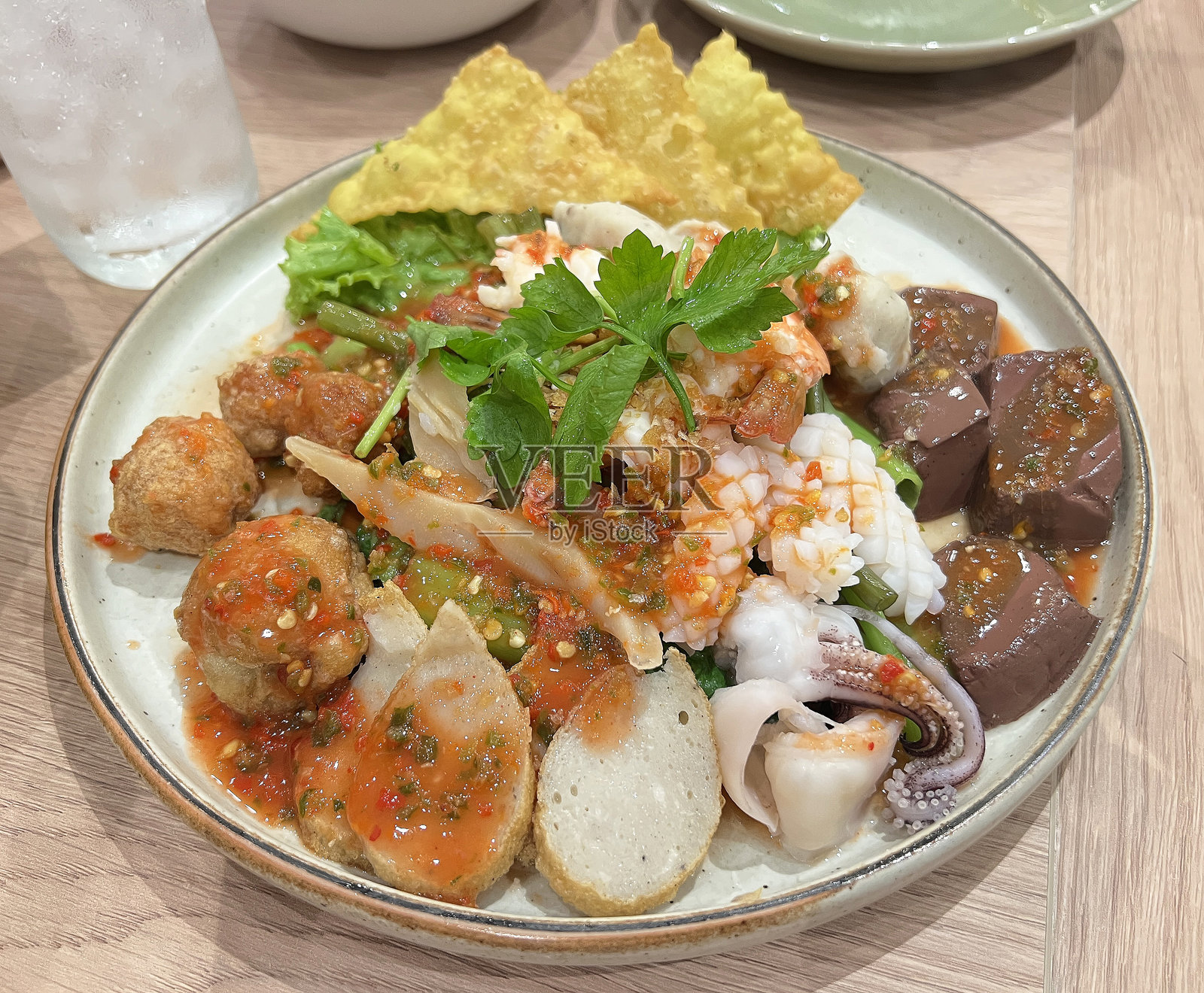 泰式辣味沙拉，配有鱼丸、虾丸、虾和鱿鱼，淋上辣酱照片摄影图片