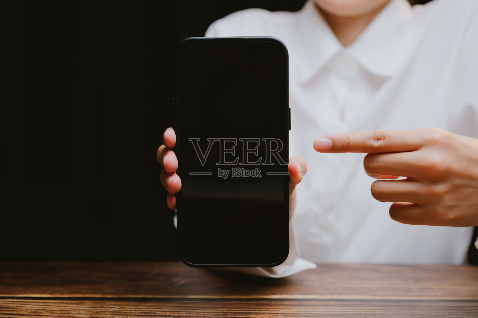 在黑暗背景下手持空白智能手机的人用于展示照片摄影图片