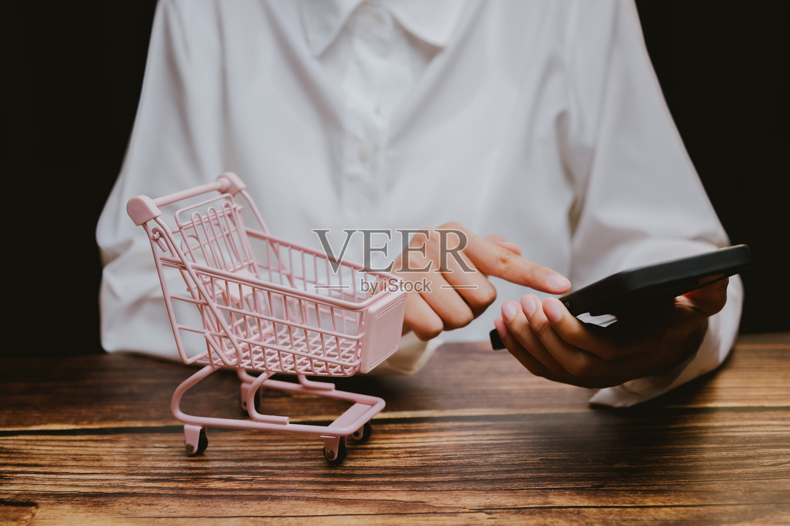 在现代环境中使用迷你购物车和智能手机进行在线购物照片摄影图片