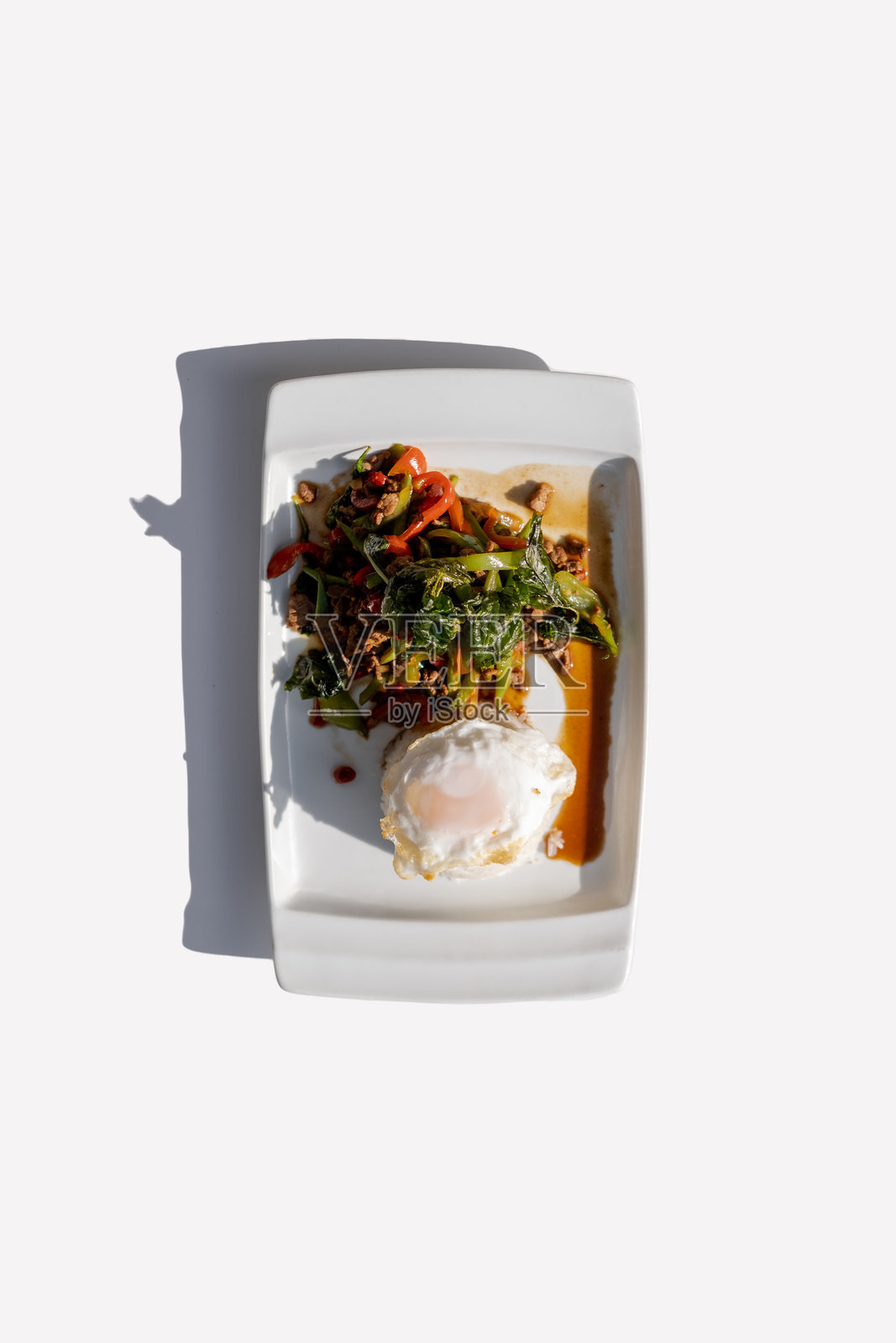 正宗泰式罗勒炒猪肉配煎蛋，盛放在白色盘子里，炒碎猪肉与圣罗勒和辣椒，传统泰国街头美食。照片摄影图片