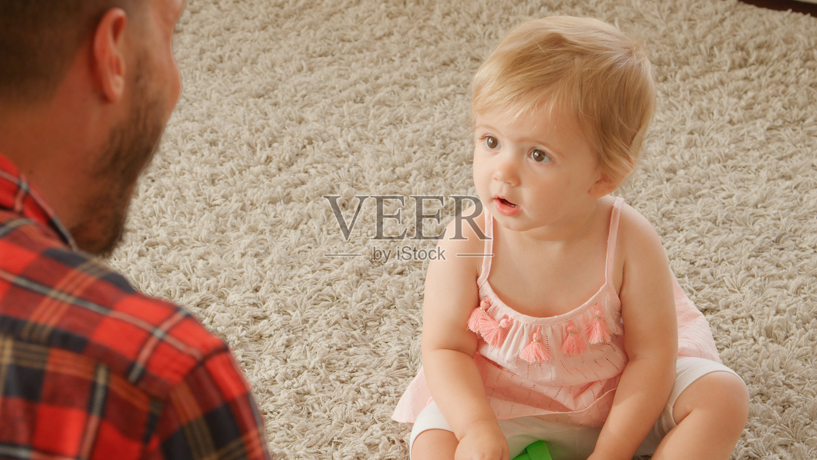 父亲坐在地板上与年轻女儿一起玩五颜六色的塑料玩具。照片摄影图片