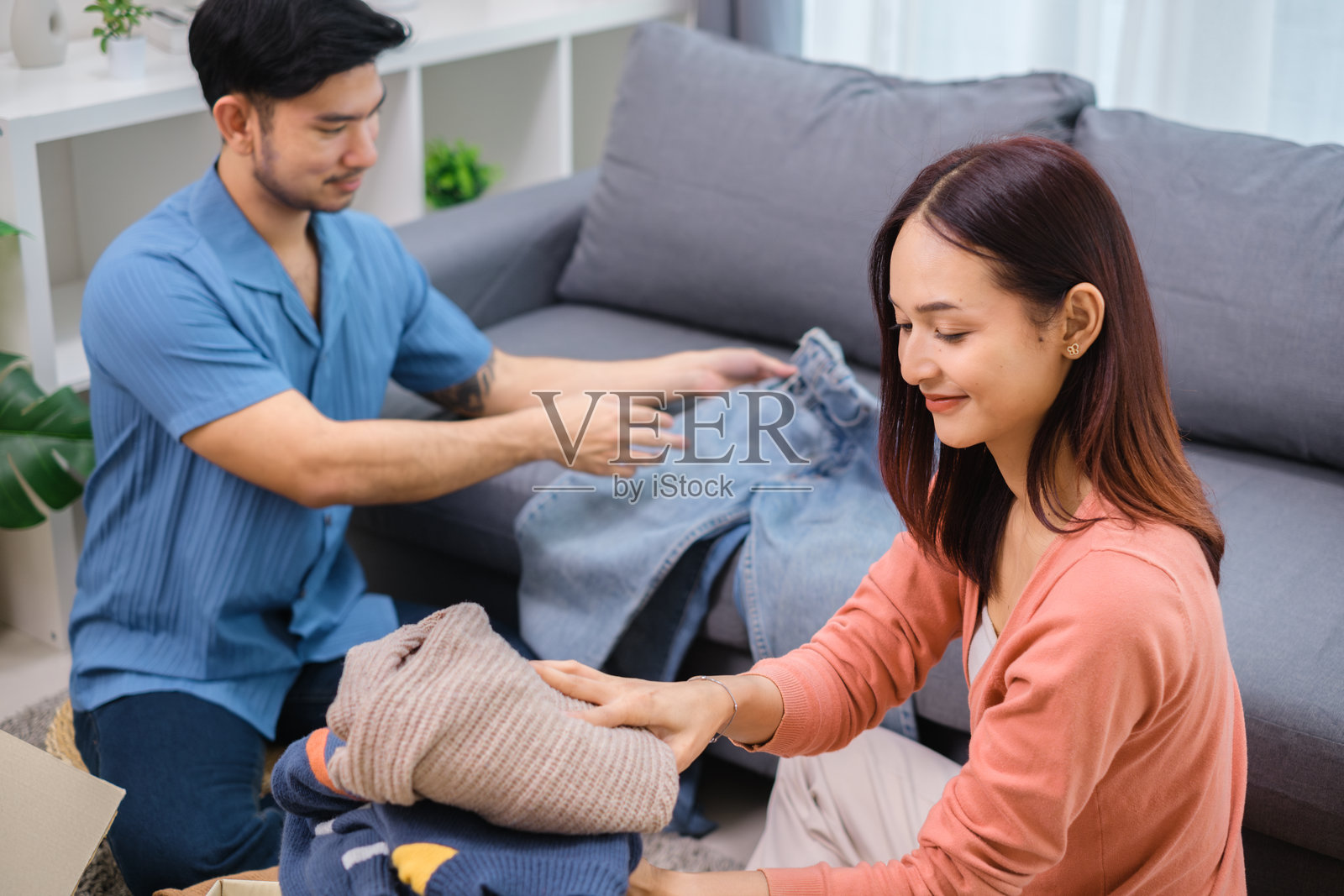 一群朋友正在整理和打包衣物放入捐赠箱，支持社区和慈善事业。照片摄影图片