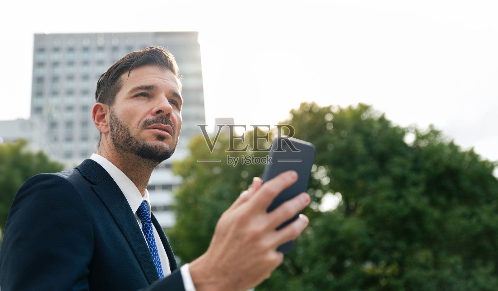 商人在现代城市的树木和建筑之间站立，ESG环境、社会和治理生态商业与可持续发展环境照片摄影图片