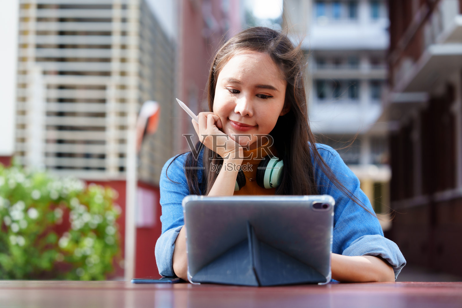 一位心情愉快的美丽女性在城市的办公大楼里站着，听着手机上的音乐。人们的生活方式。照片摄影图片