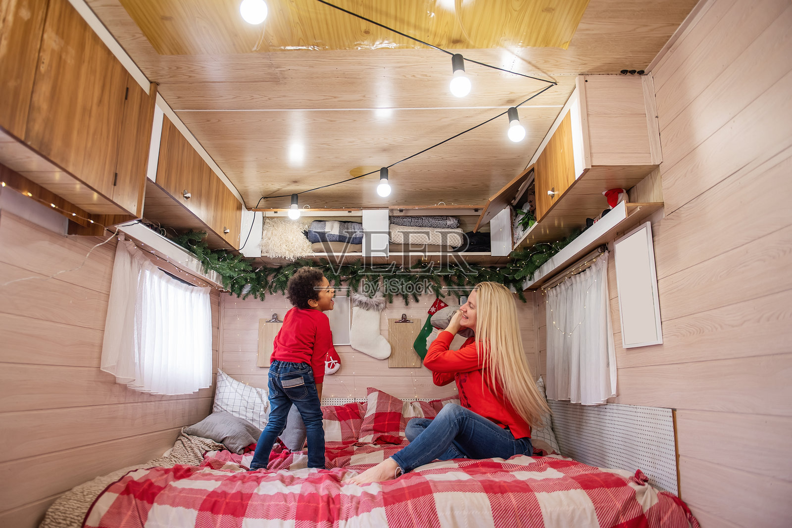 母亲和小儿子在节日露营车中享受枕头大战照片摄影图片