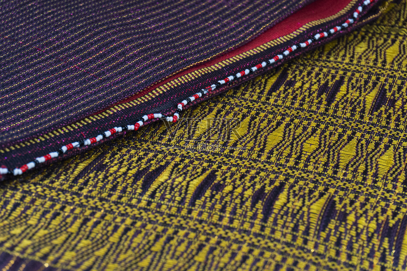 丰富的金色和深紫色的民族纺织品分层组合，饰有珠饰细节，捕捉传统工艺的精髓。照片摄影图片