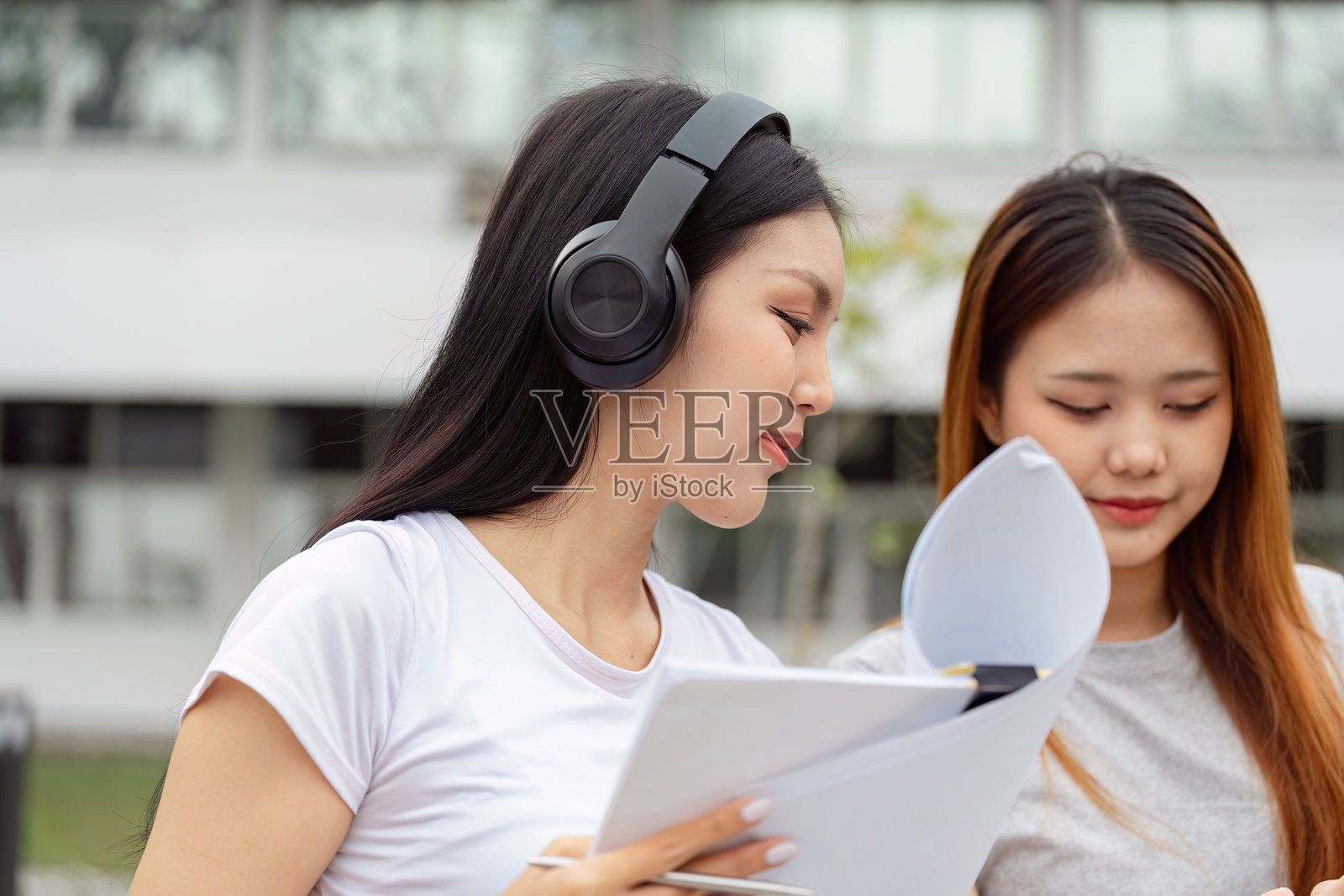 专注的学生在户外合作，佩戴耳机并使用学习材料照片摄影图片