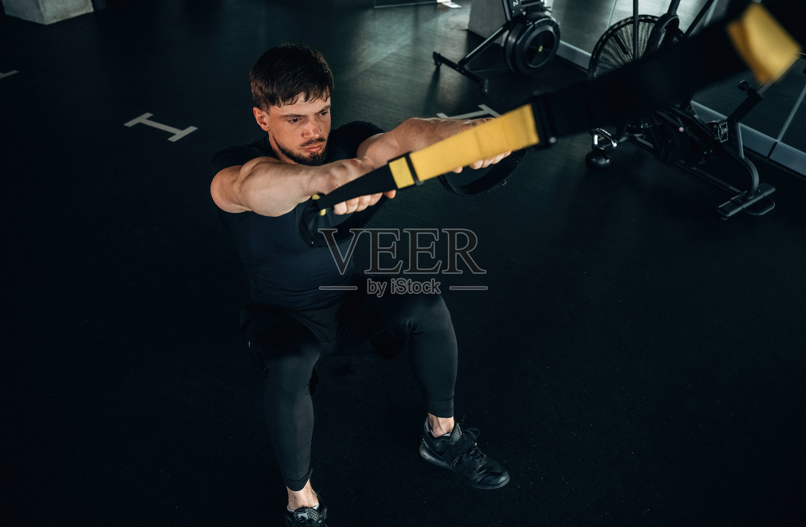 男子在现代健身房进行拉绳胸部锻炼。照片摄影图片