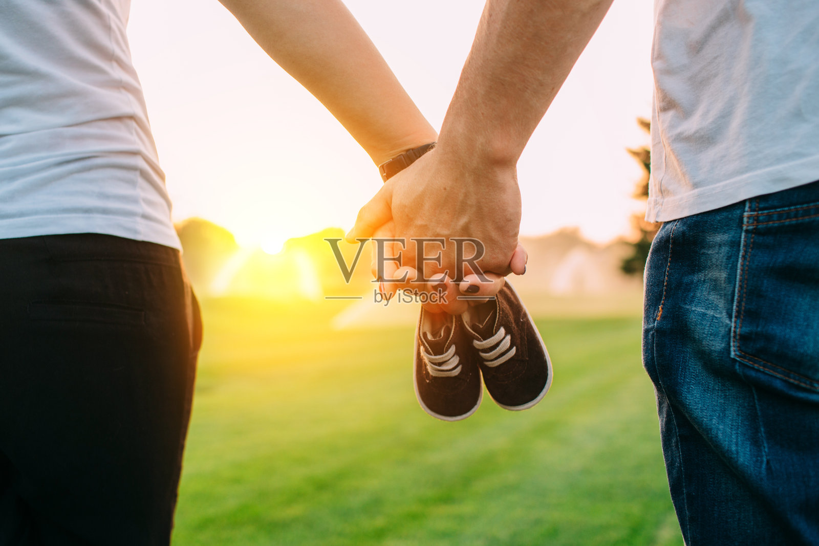 一对夫妇手持婴儿鞋，期待着宝宝的到来。照片摄影图片