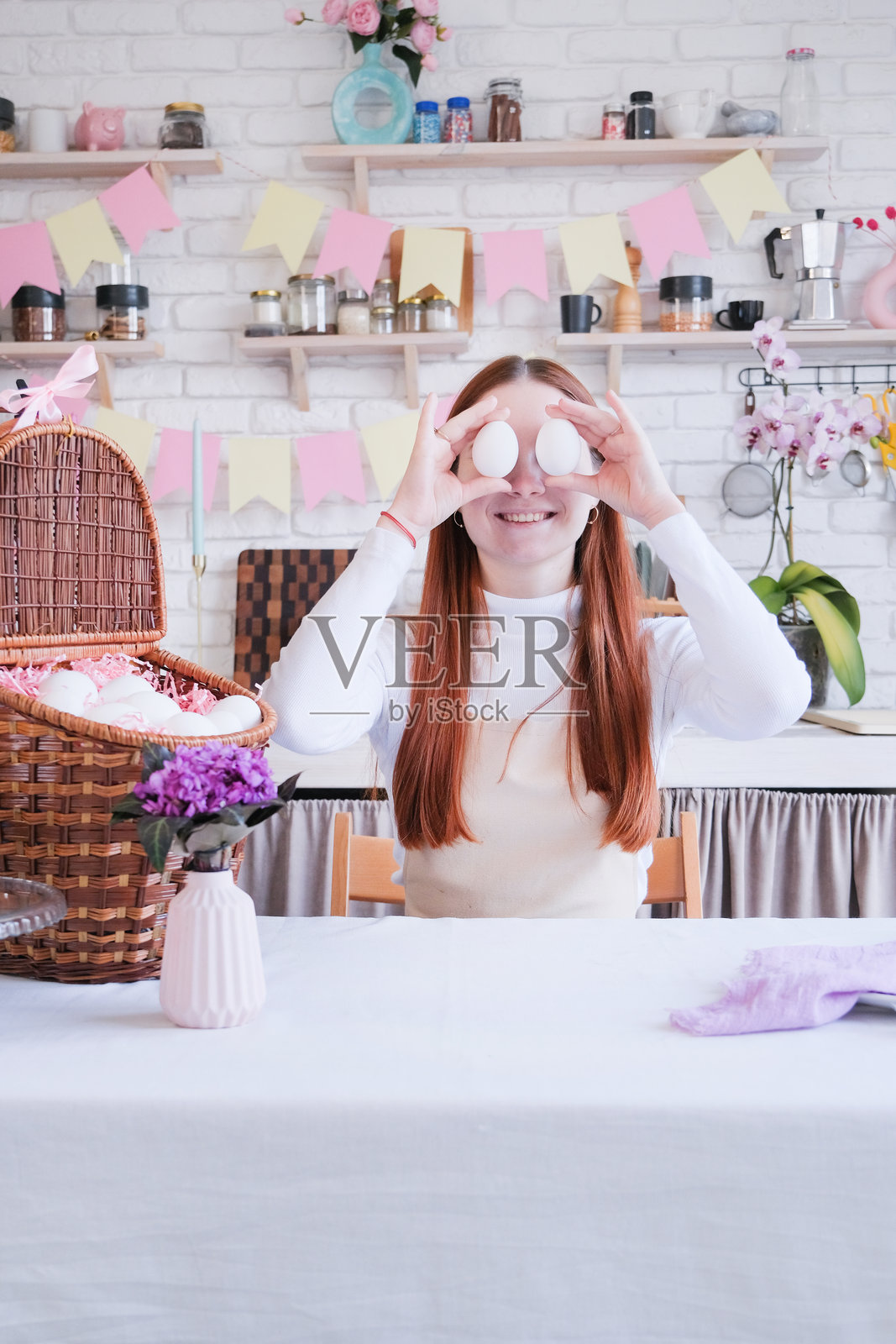穿围裙的女人正在给白色复活节彩蛋上色，为复活节做准备照片摄影图片