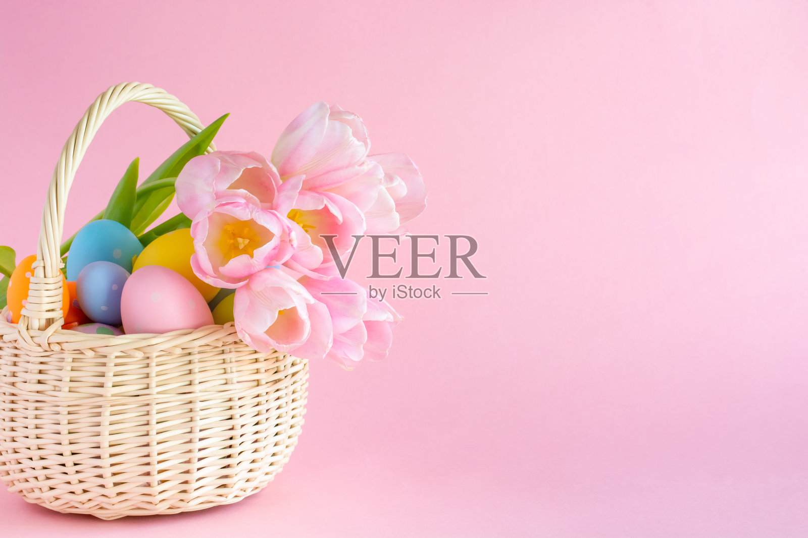 粉色纸背景上的复活节彩蛋和郁金香的篮子，留白空间照片摄影图片