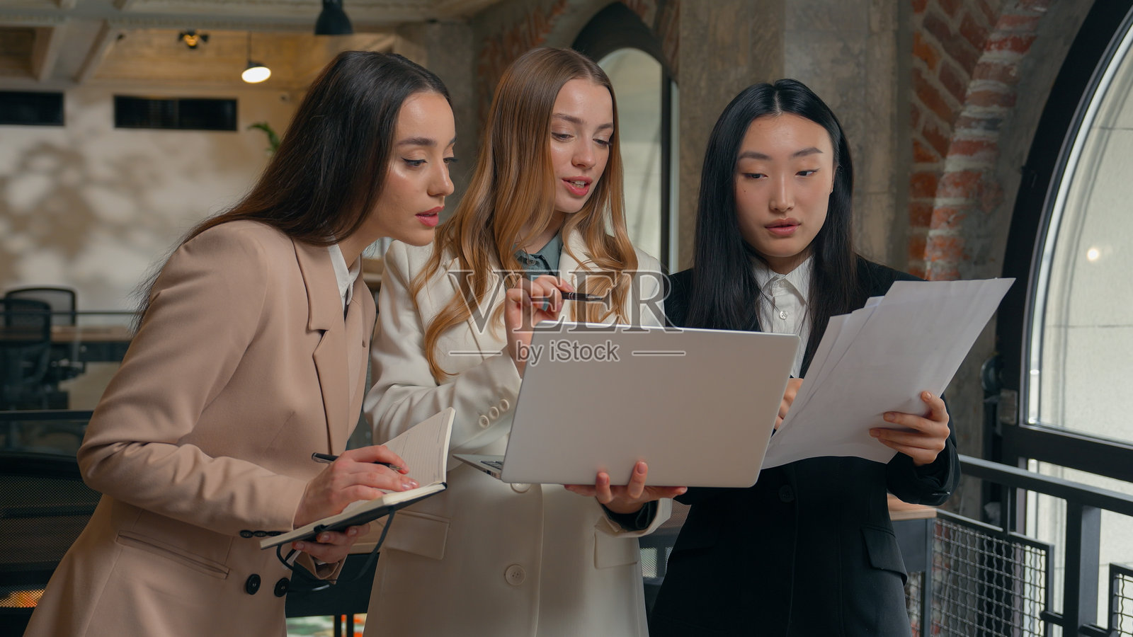 商业团队合作头脑风暴，笔记本电脑、文件、数据，三位多元文化女性，亚洲、韩国、中国、日本、白人女孩在办公室交谈讨论照片摄影图片