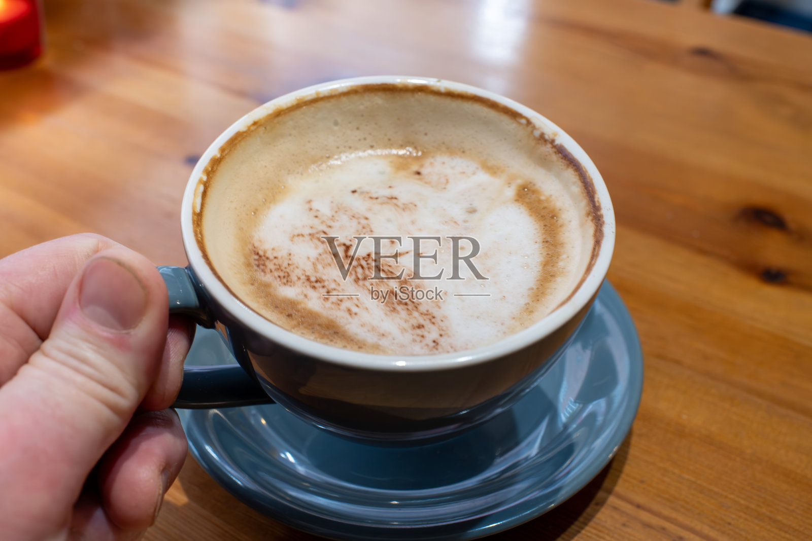 一只手握着一杯顶部有白色泡沫的咖啡照片摄影图片