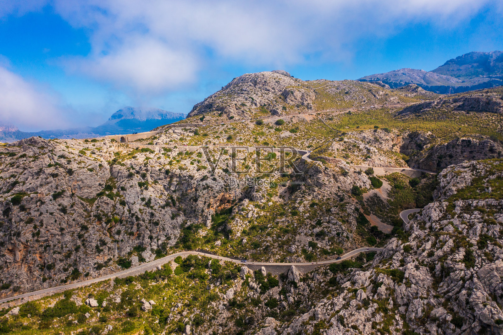 令人惊叹的空中拍摄，标志性的萨卡洛布拉公路蜿蜒穿过马洛卡的特拉蒙塔纳山脉。蜿蜒的山路，急转弯，是旅行者和骑行爱好者的热门目的地。照片摄影图片