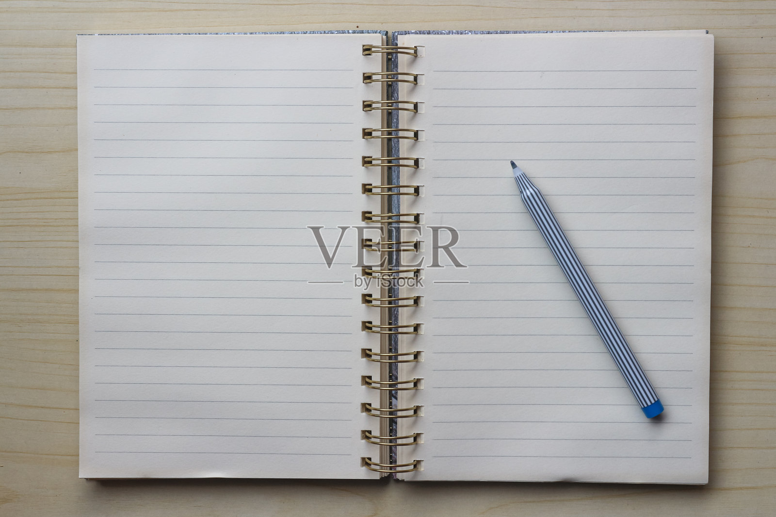 空白的打开笔记本或活页夹，旁边放着一支笔，置于木桌上照片摄影图片