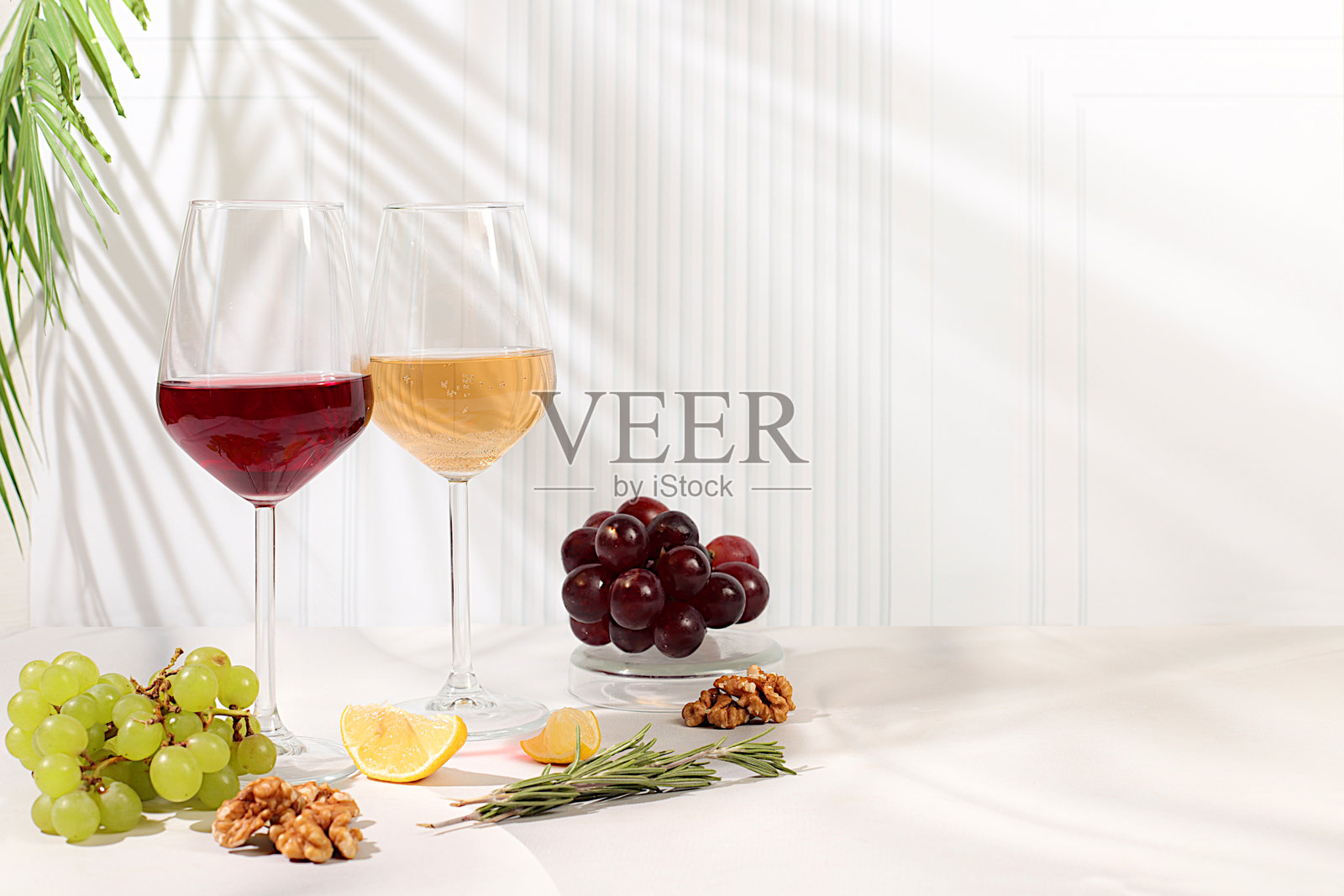 品尝高贵的红白葡萄酒，搭配葡萄品种、坚果和迷迭香，酒会和夏季派对的概念。咖啡馆和餐厅的广告横幅，现代静物。照片摄影图片