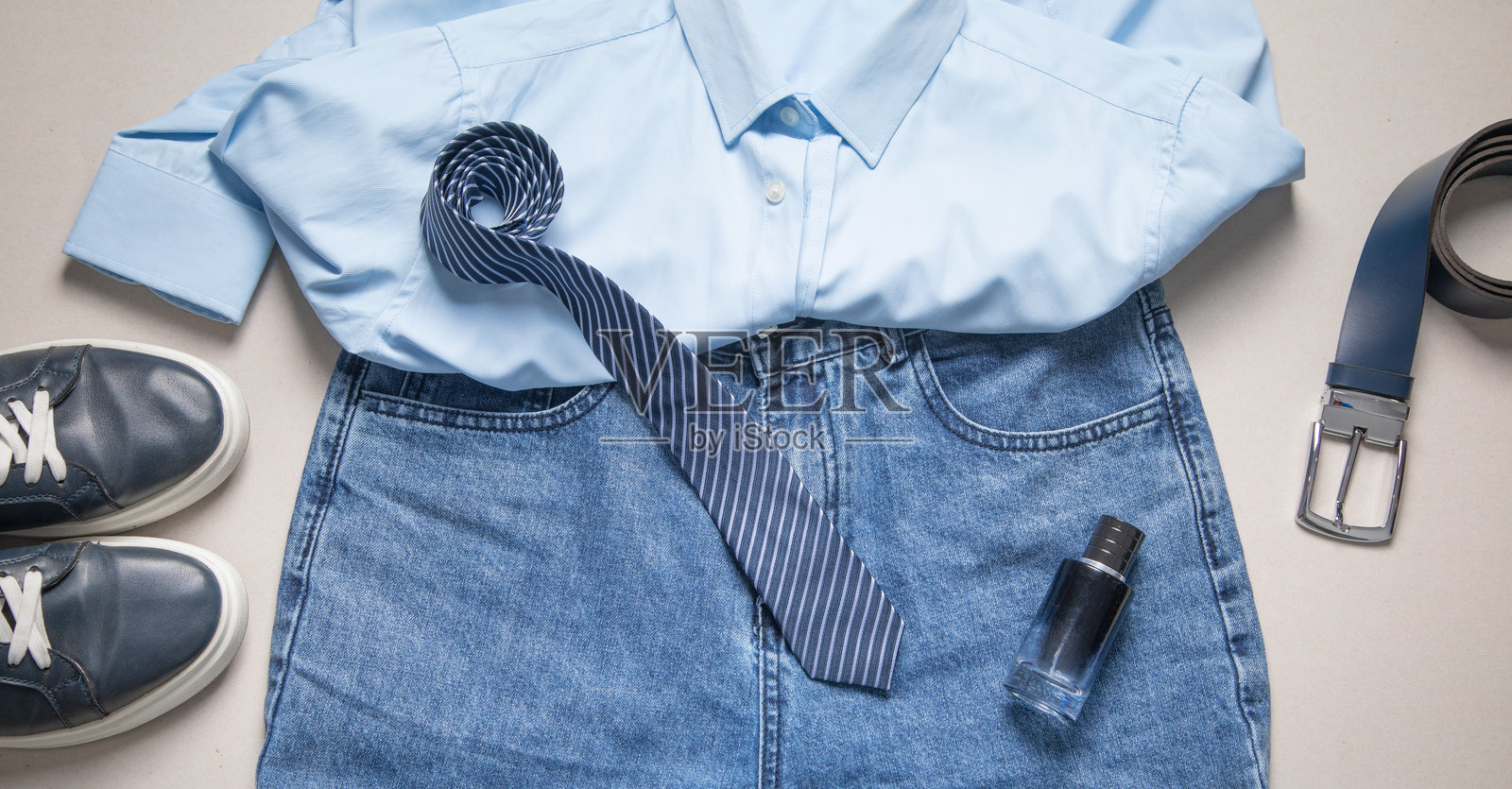 灰色背景上的蓝色牛仔裤、皮带和其他物品。照片摄影图片