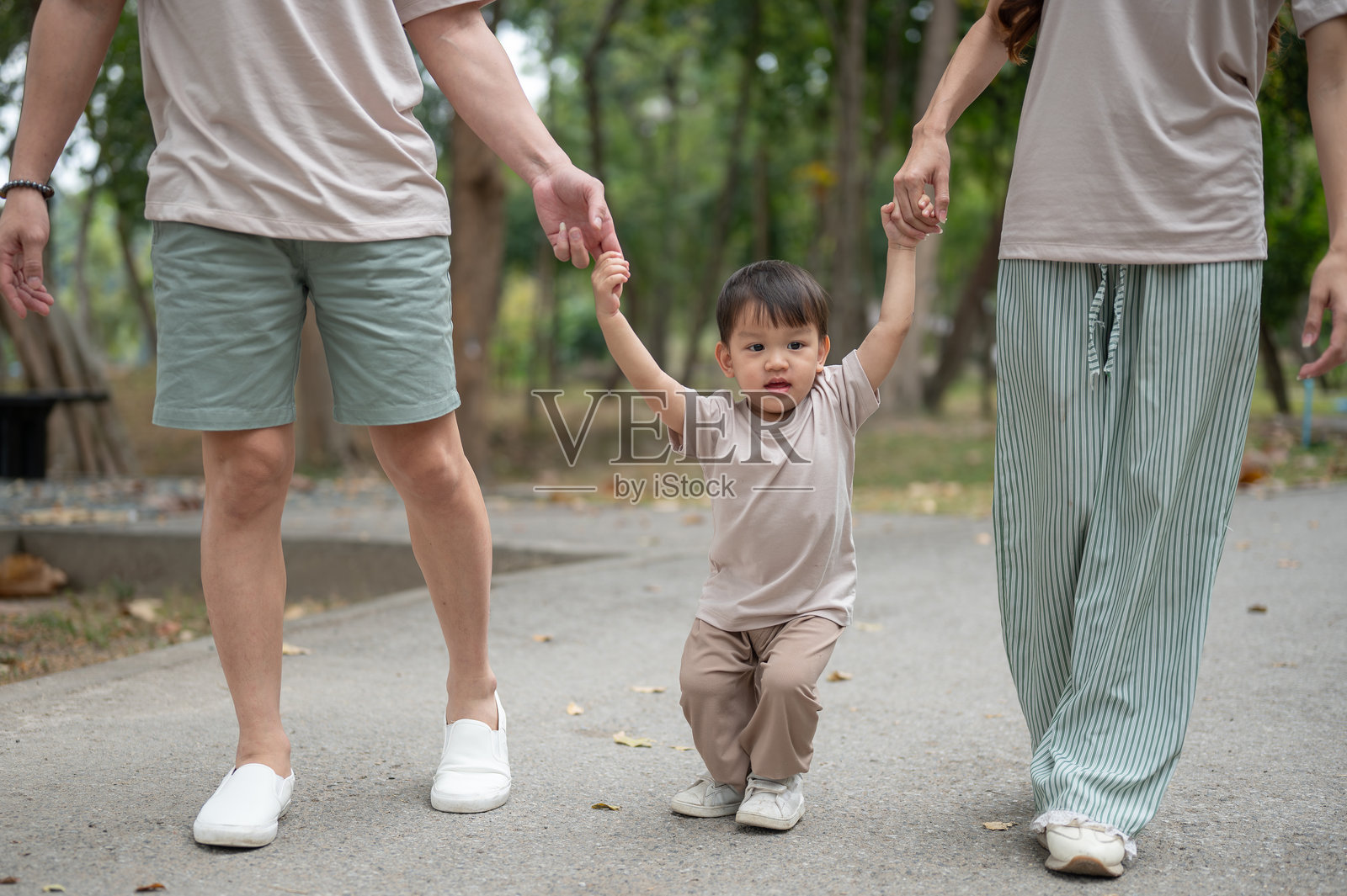 可爱快乐的小亚洲男孩在公园里牵着父母的手走路的特写镜头照片摄影图片