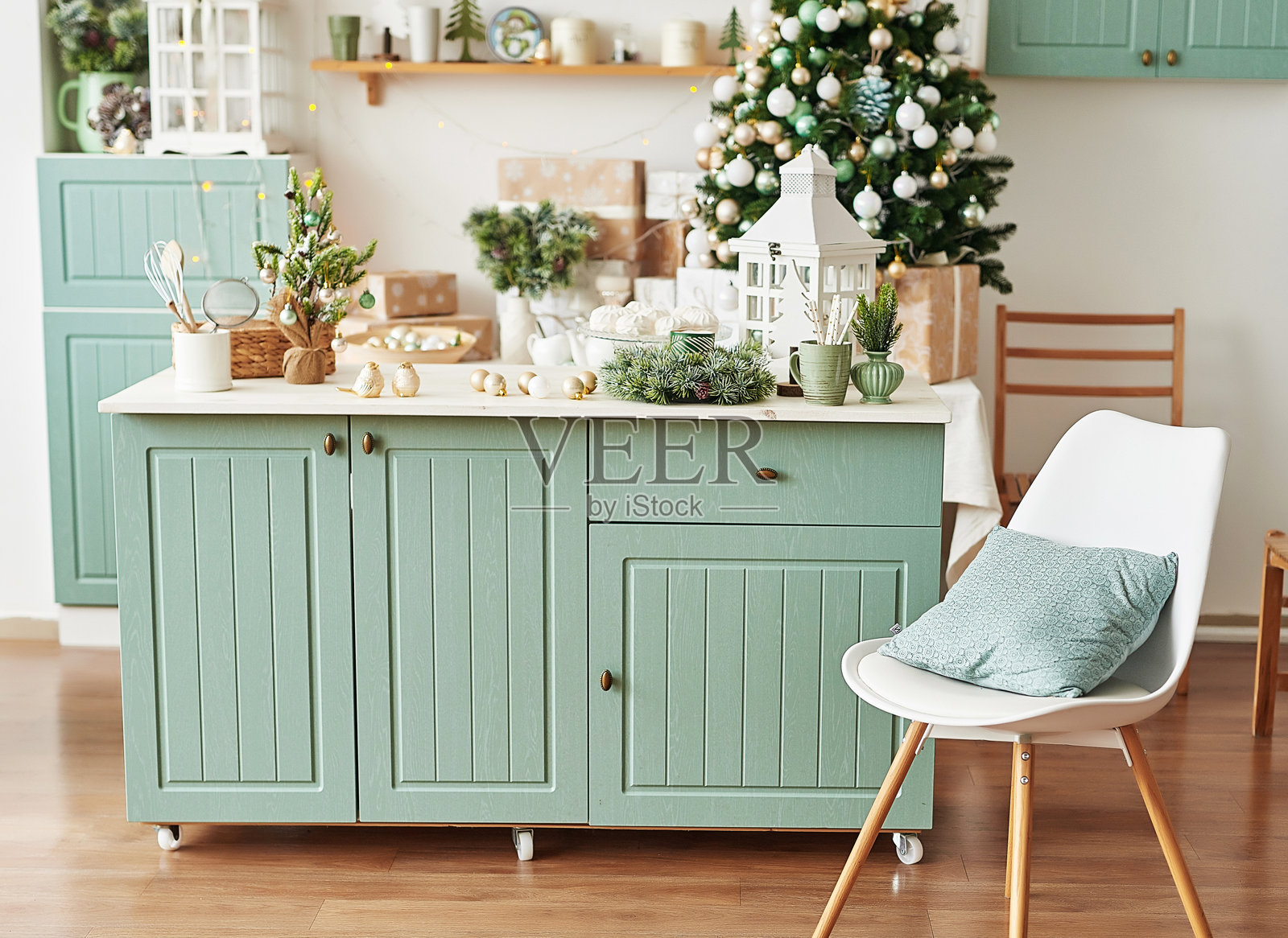 带有圣诞装饰和圣诞树的室内明亮厨房。经典风格的蓝绿色厨房。厨房里的圣诞节。明亮的薄荷绿和白色调的厨房与圣诞节装饰。照片摄影图片