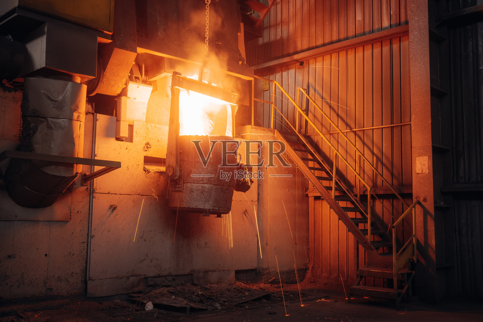 熔融金属在工业铸造厂倾倒，火花四溅，发光的液体被转移。照片摄影图片