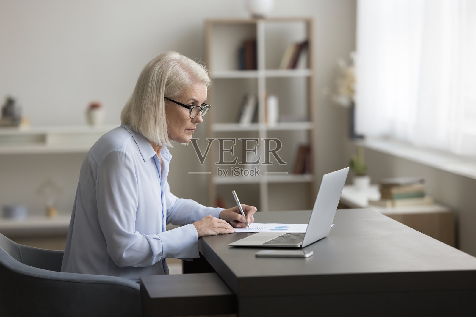 女商人在桌子前工作，查看信息图表数据，准备财务报告照片摄影图片