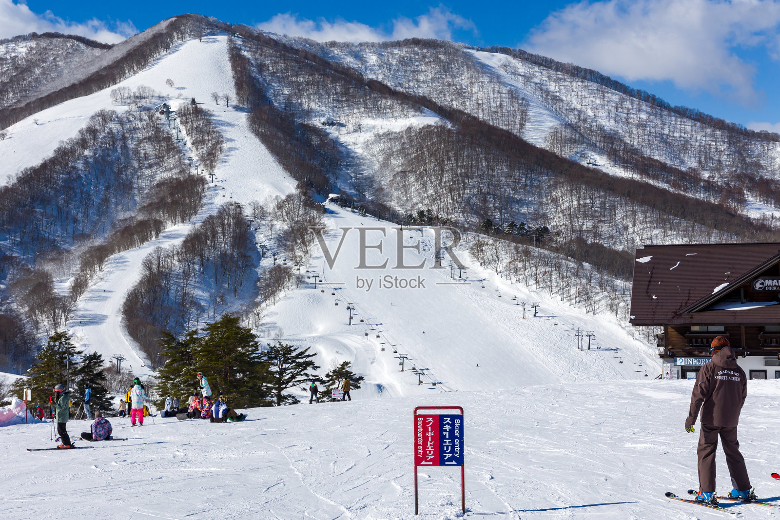 在阳光明媚、蓝天的冬日，滑雪者和单板滑雪者在日本的斑鸠滑雪度假村享受滑雪乐趣。照片摄影图片