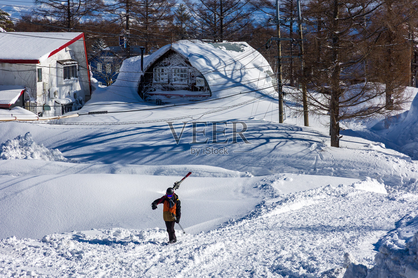 滑雪者和单板滑雪者在长野县的斑鸠山，刚刚经历了一场新雪风暴后，沿着被雪覆盖的道路行走。照片摄影图片