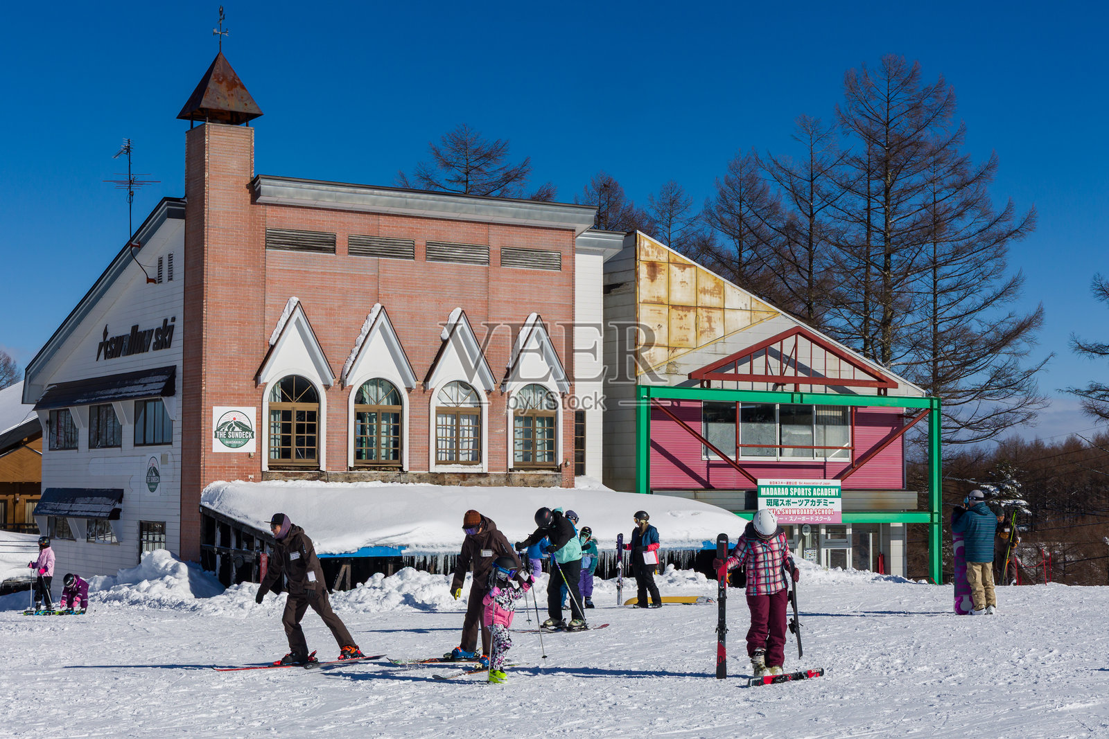 在阳光明媚、蓝天的冬日，滑雪者和单板滑雪者在日本的斑鸠滑雪度假村享受滑雪乐趣。照片摄影图片