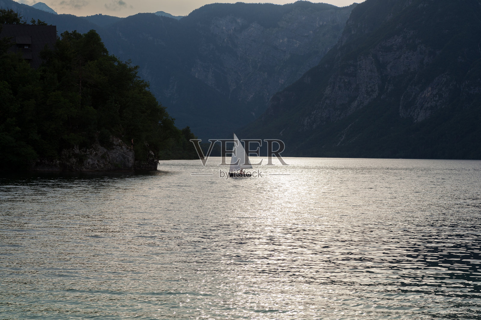 斯洛文尼亚博希尼湖上的帆船在雾气弥漫中航行。照片摄影图片