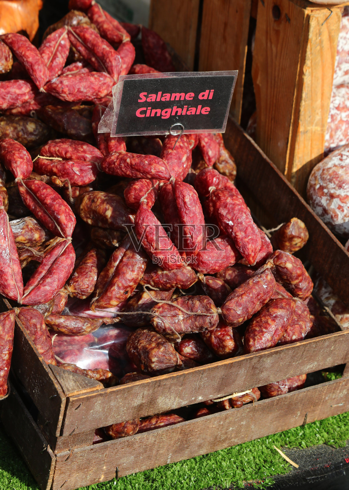 装满野猪肉小香肠的箱子，放在意大利食品摊位上，标签上有意大利语文字照片摄影图片