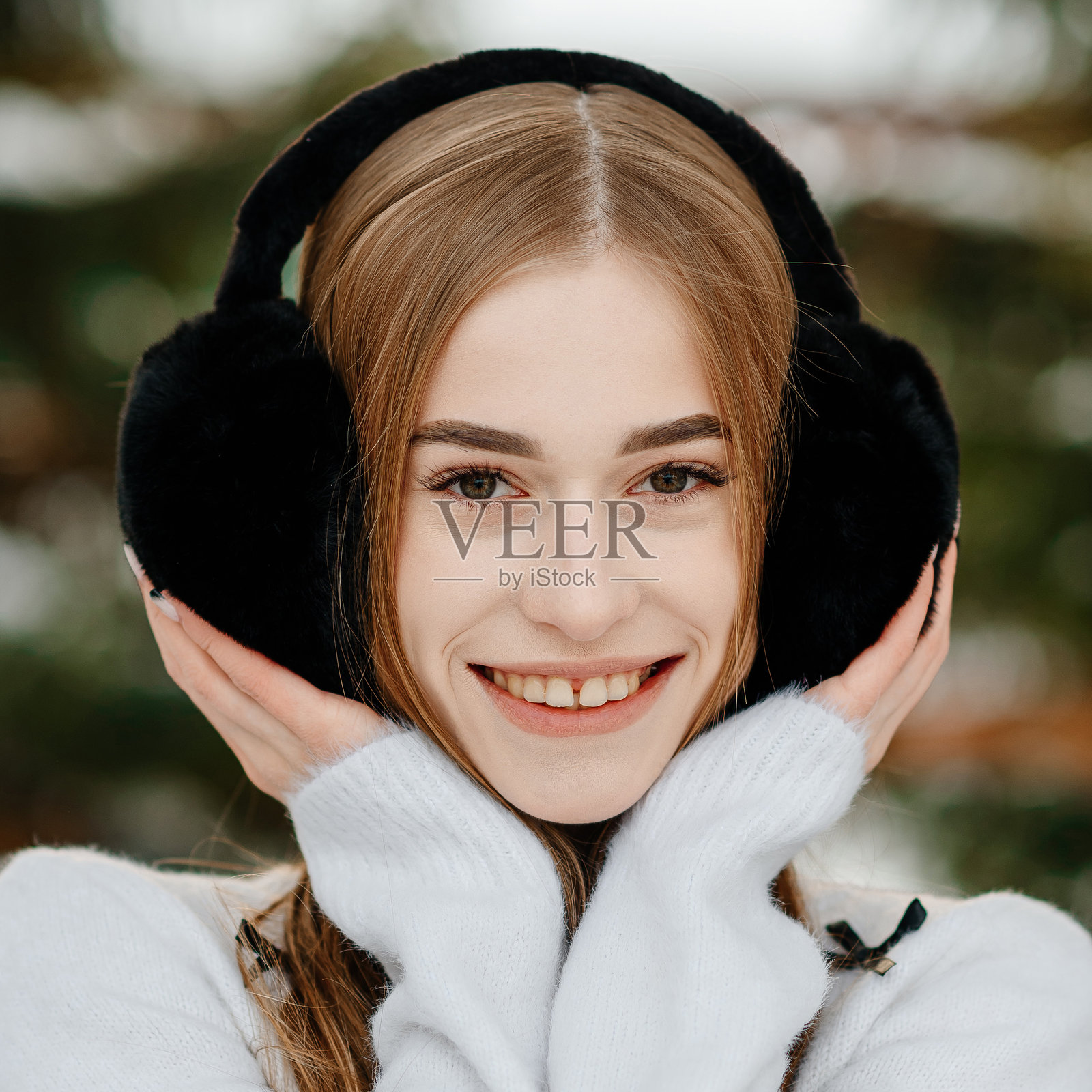 年轻的金发女性穿着白色毛衣和黑色耳机照片摄影图片