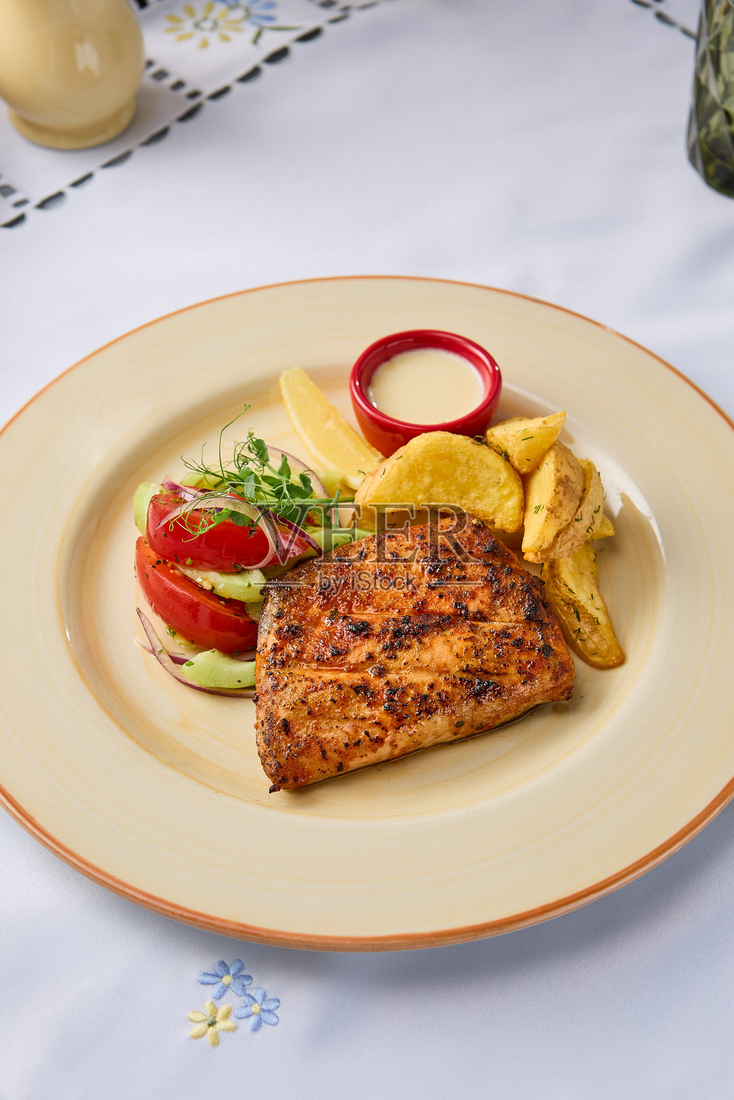 在明亮自然光下的烤鳟鱼配烤土豆和新鲜蔬菜沙拉照片摄影图片