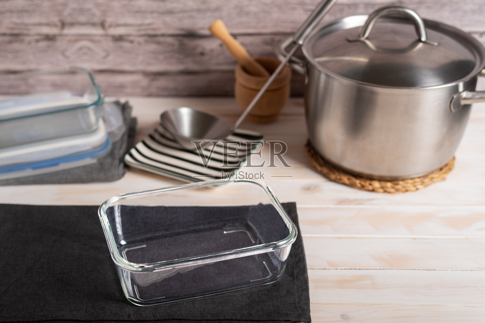 玻璃食品容器放在锅旁边，旁边有一个汤勺和另一个食品容器，特写。照片摄影图片