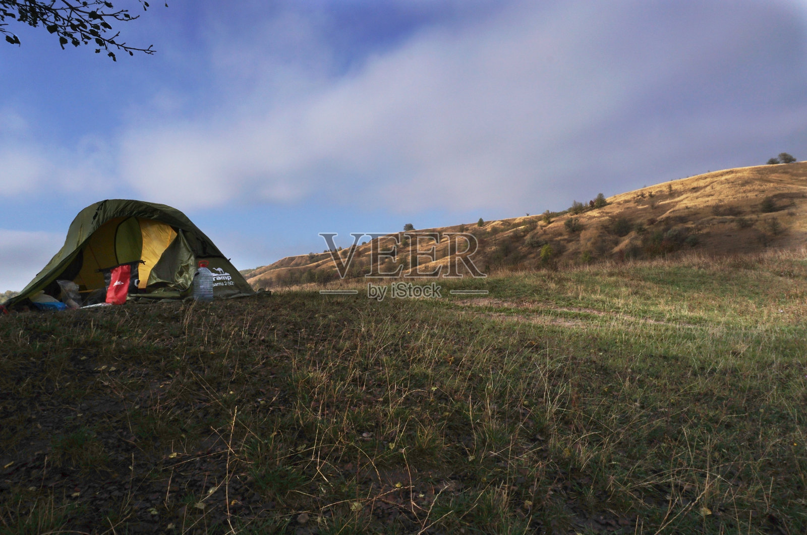 在五彩斑斓的丘陵下露营于河边照片摄影图片