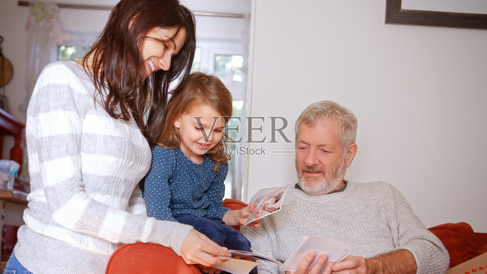 多代家庭坐在家里的沙发上查看照片照片摄影图片