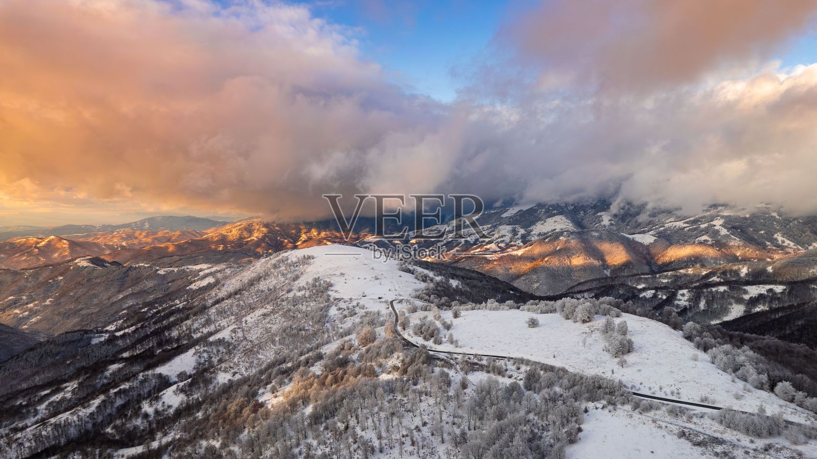 日落时分的雪覆盖山脉的鸟瞰图。照片摄影图片