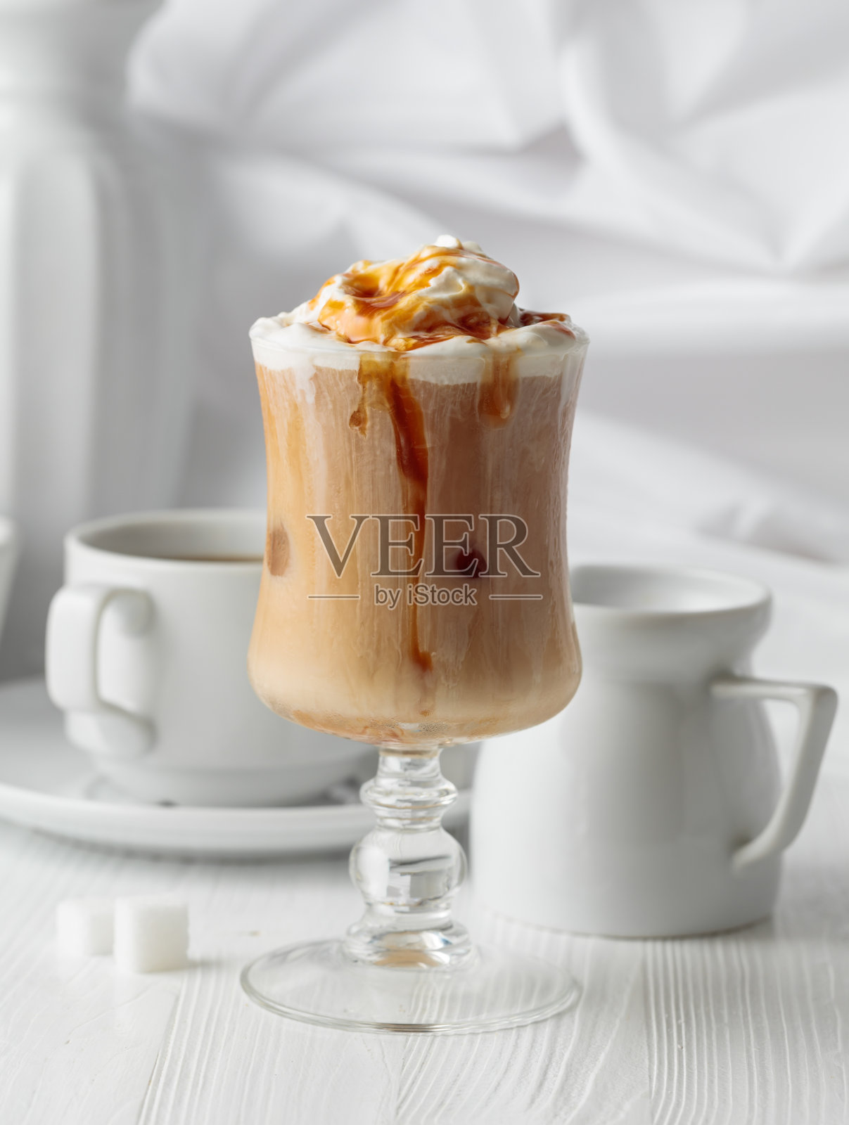 冰镇焦糖拿铁，上面装饰有鲜奶油和焦糖酱。照片摄影图片