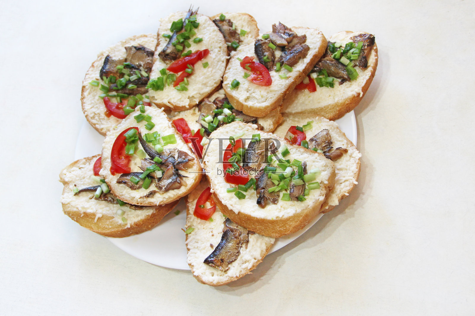 盘子上的小鱼和葱花吐司。冷盘开胃菜。三明治。照片摄影图片