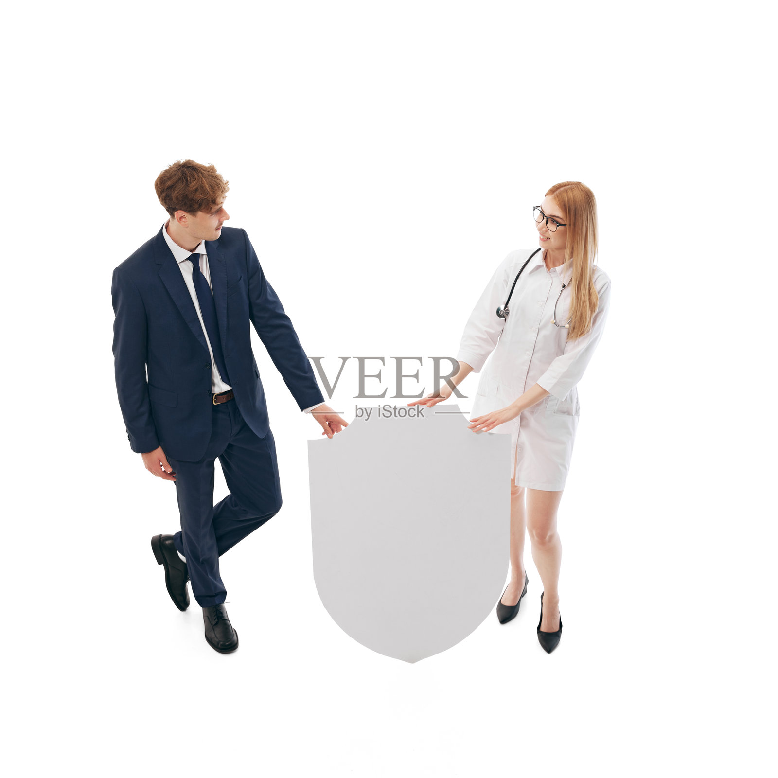 医生和商人讨论医疗保障，站在巨大的盾牌旁边照片摄影图片