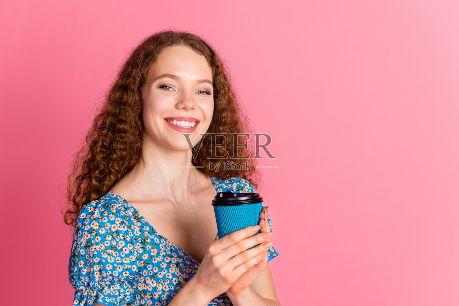 微笑的女性手持咖啡杯，背景为粉色照片摄影图片