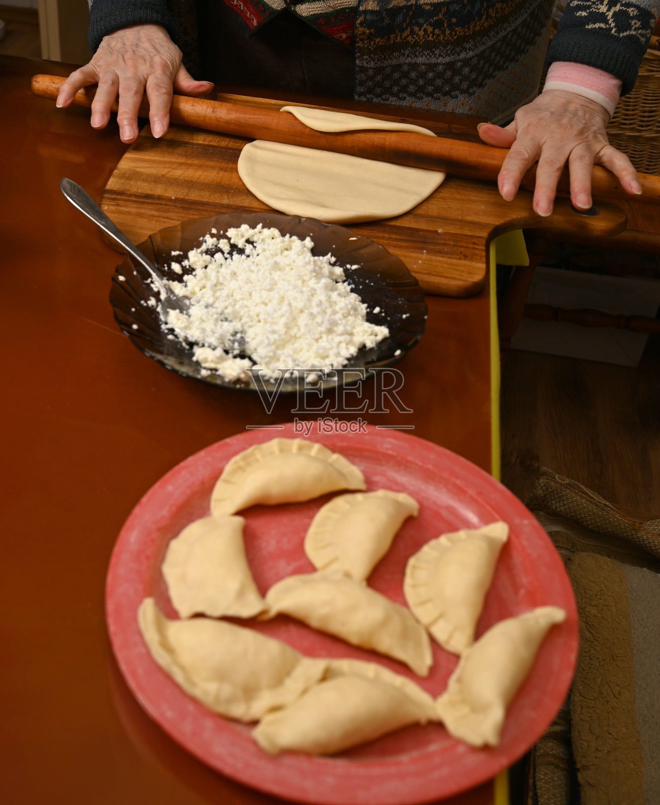 在温馨的厨房环境中，木质台面上正在准备自制的奶酪馅饺子照片摄影图片