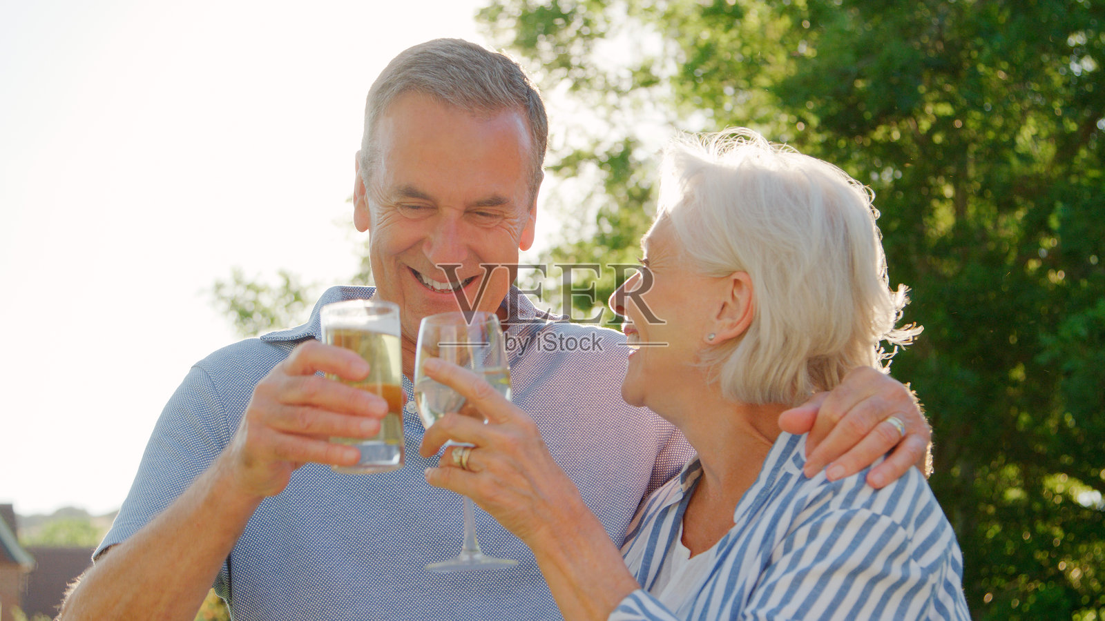 老年夫妇在酒吧享受户外夏季饮品，举杯庆祝照片摄影图片