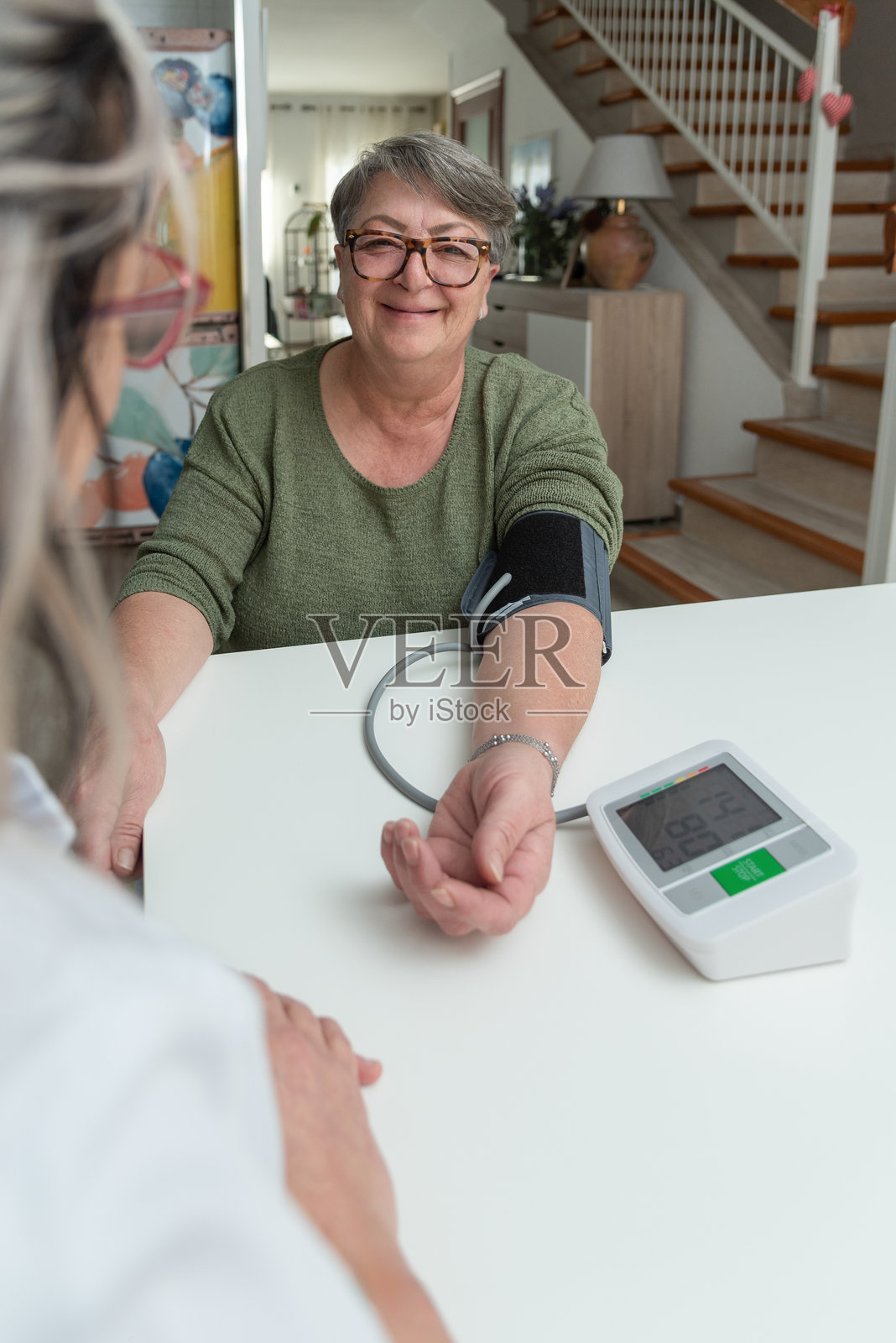医生在家中为老年女性测量血压照片摄影图片