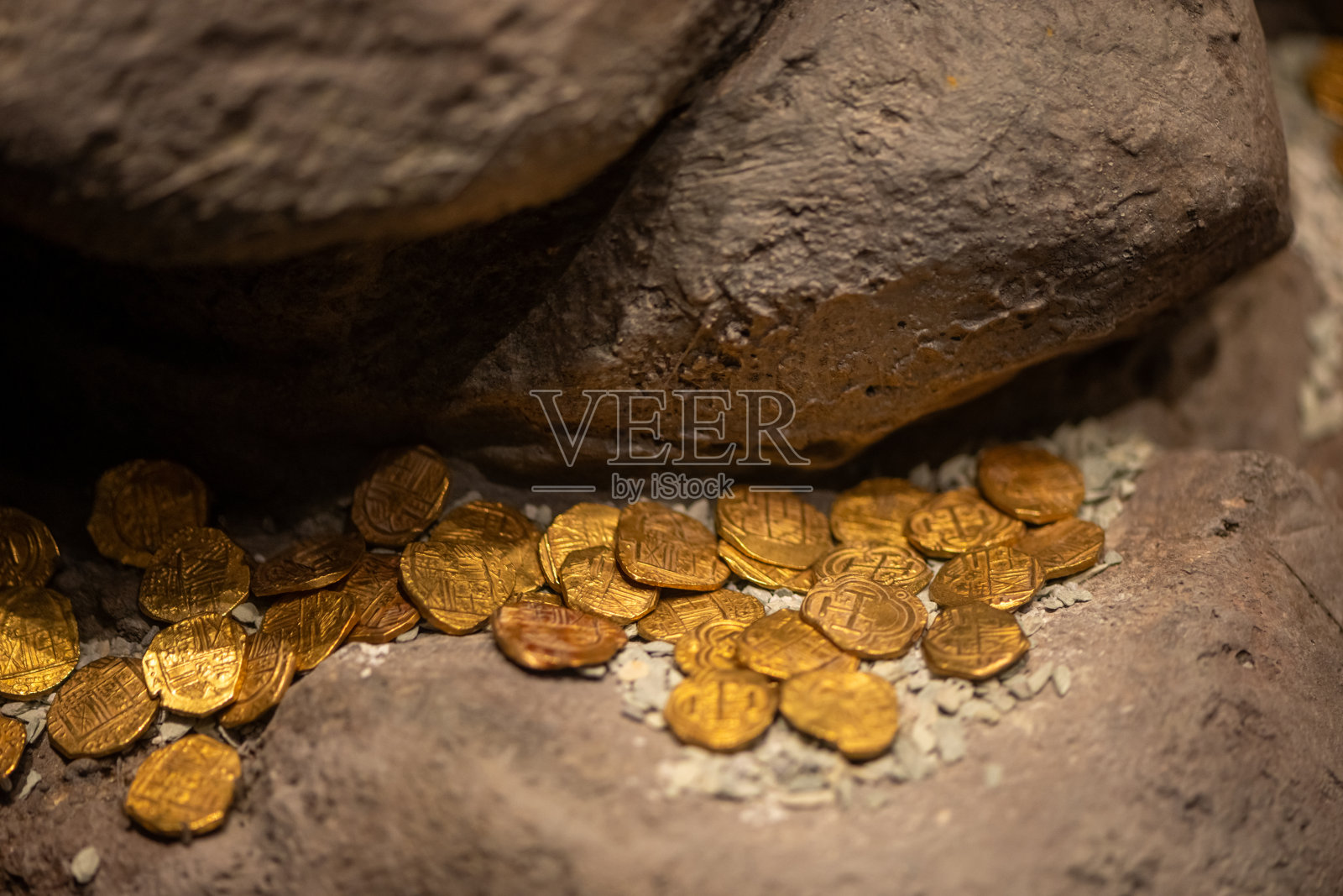 古老的殖民时期金币静静地 resting 在大石头上，仿佛隐藏的宝藏照片摄影图片