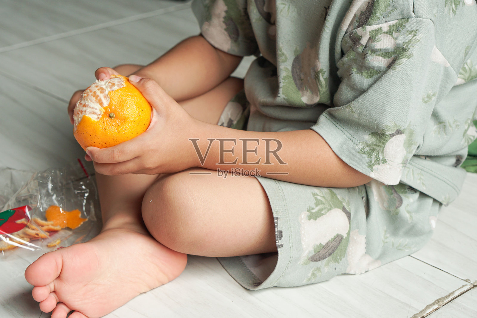 幼儿尝试剥去橘子的皮，进行儿童感官训练。早期探索和学习水果。儿童成长概念。照片摄影图片