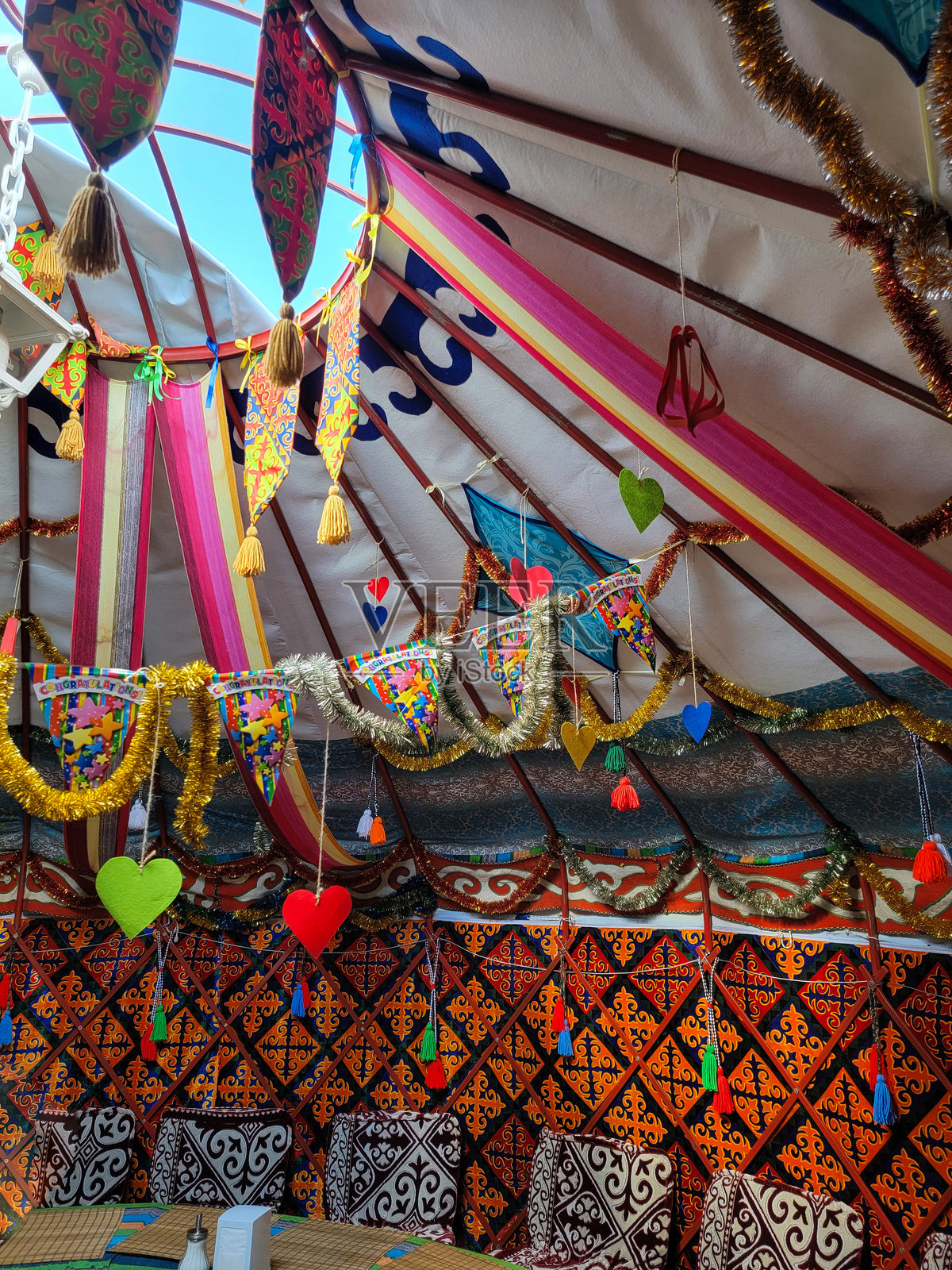 一个色彩斑斓的帐篷，中央有一个大圆孔，烟囱在吉尔吉斯斯坦的传统游牧毡房中。照片摄影图片